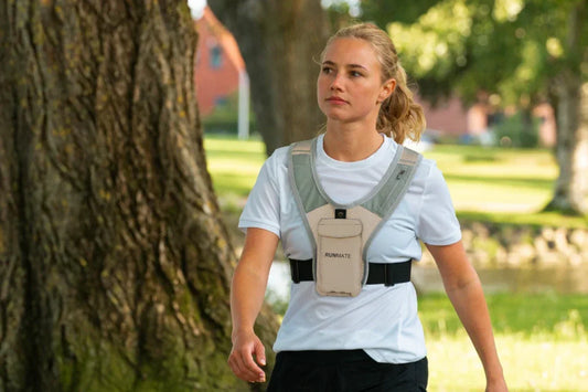 Kvinde går i park med løbevest fra RUNMATE på
