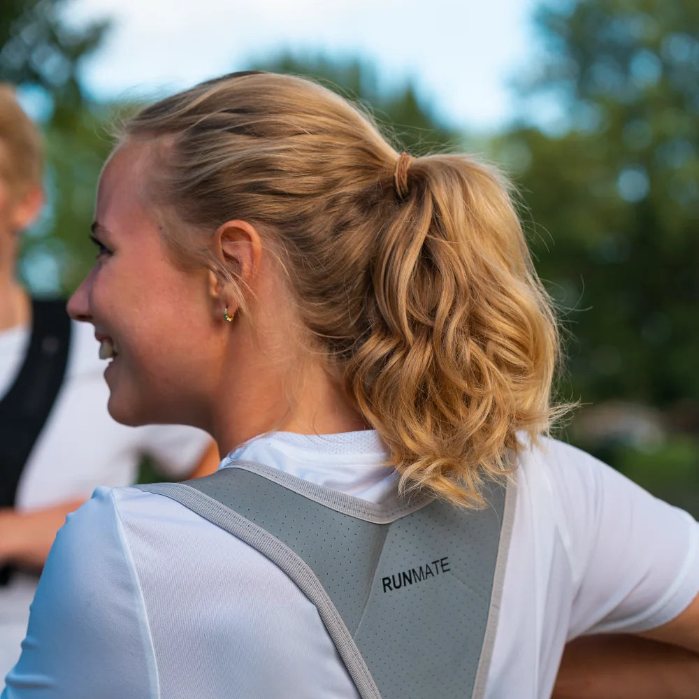 Dette er et billede af en kvinde i en løbevest i refleks fra RUNMATE set bagfra i en park