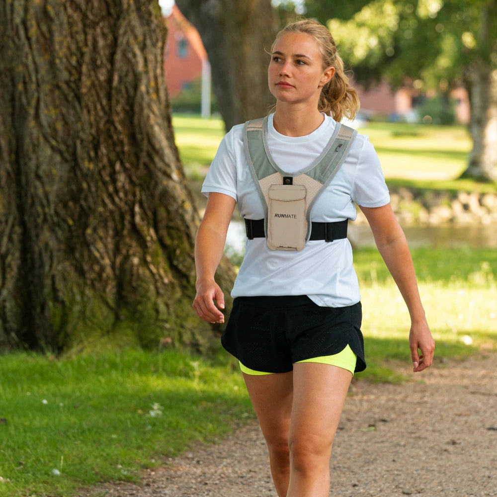 Dette er et billede af en kvinde i en refleks løbevest fra RUNMATE, som går i en park