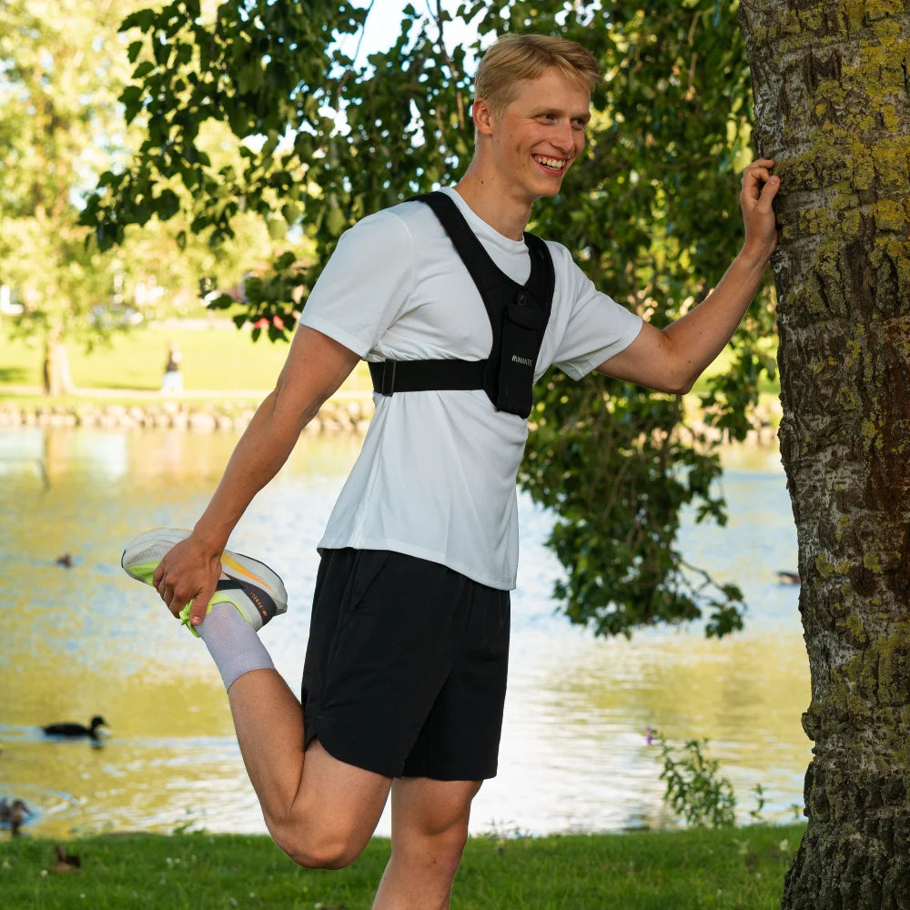 Dette er et billede af en mand i en sort løbevest fra RUNMATE, som er i naturen