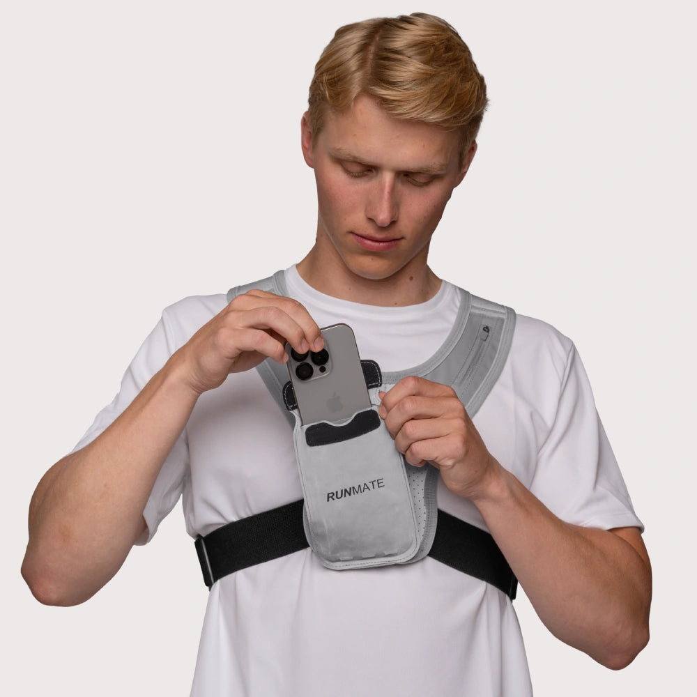 Dette er et billede af en mand i en refleks løbevest fra RUNMATE, som sætter sin mobil i mobilholderen